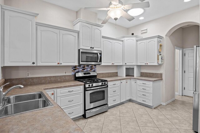 5339 Pond Crossing Pl, Leesburg, FL 34748 - kitchen with appliances with stainless steel finishes, white cabinets, ceiling fan, arched walkways, and light tile patterned floors