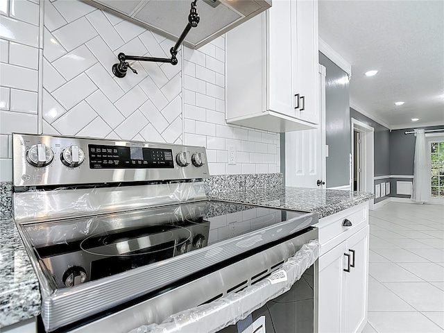 3417 Pershing Ave, Orlando, FL 32812 - kitchen with electric range, light stone counters, white cabinets, ornamental molding, and light tile patterned floors