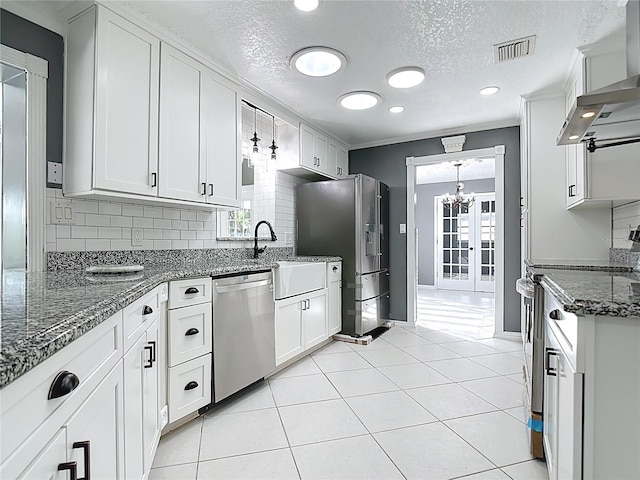3417 Pershing Ave, Orlando, FL 32812 - kitchen with stainless steel appliances, wall chimney range hood, a chandelier, backsplash, and a textured ceiling