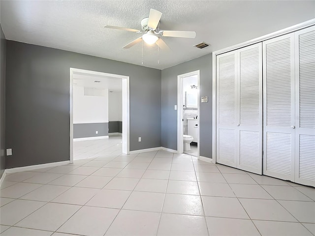 3417 Pershing Ave, Orlando, FL 32812 - unfurnished bedroom with a closet, a textured ceiling, light tile patterned floors, connected bathroom, and ceiling fan