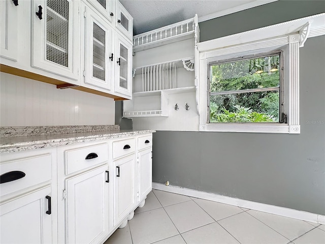 3417 Pershing Ave, Orlando, FL 32812 - kitchen featuring white cabinets, light tile patterned floors, glass insert cabinets, open shelves, and light stone countertops