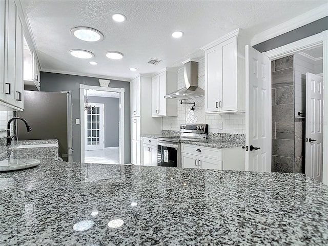 3417 Pershing Ave, Orlando, FL 32812 - kitchen with stainless steel appliances, wall chimney range hood, dark stone counters, white cabinets, and a textured ceiling