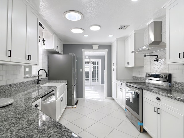 3417 Pershing Ave, Orlando, FL 32812 - kitchen featuring wall chimney range hood, appliances with stainless steel finishes, a textured ceiling, decorative backsplash, and white cabinetry