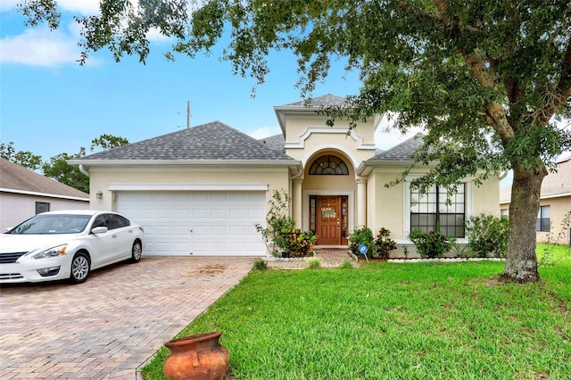 501 Lake Cummings Way, Lake Alfred, FL 33850 - view of front facade featuring stucco siding, a garage, decorative driveway, a front yard, and a shingled roof
