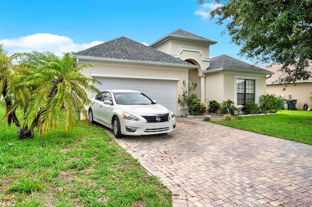 501 Lake Cummings Way, Lake Alfred, FL 33850 - view of front of property featuring decorative driveway, stucco siding, an attached garage, a front lawn, and a shingled roof