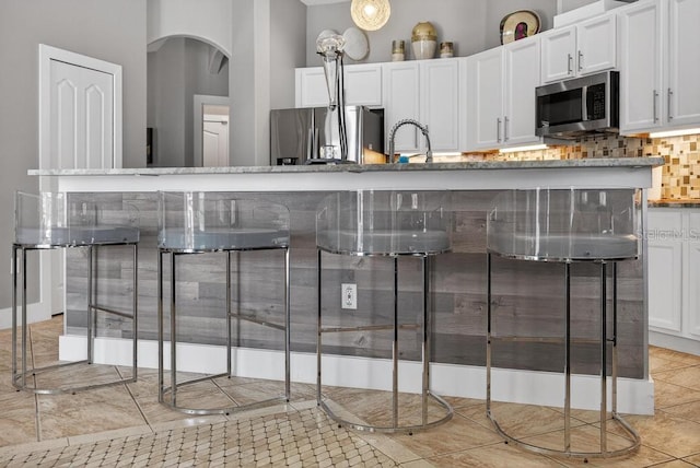 533 Quail Down Dr, Debary, FL 32713 - kitchen with stainless steel appliances, arched walkways, white cabinetry, tasteful backsplash, and light tile patterned floors