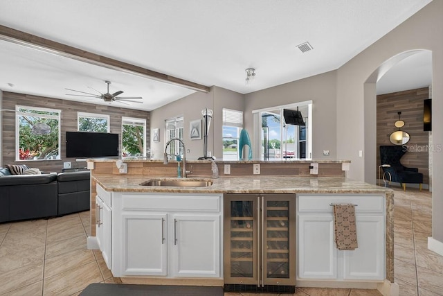 533 Quail Down Dr, Debary, FL 32713 - kitchen featuring wine cooler, open floor plan, light stone countertops, white cabinets, and beam ceiling
