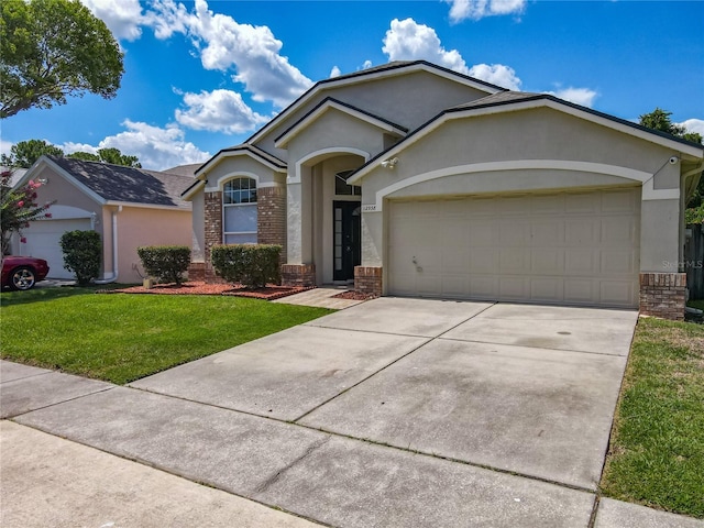 12938 Maribou Cir, Orlando, FL 32828 - ranch-style house with brick siding, stucco siding, a garage, a front yard, and concrete driveway