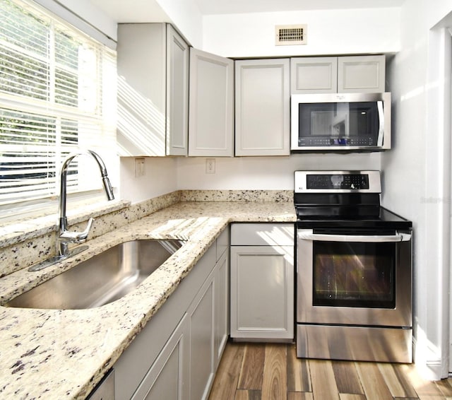 3057 Aaron Burr Ave Unit 1, Winter Park, FL 32792 - kitchen with stainless steel appliances, gray cabinetry, wood finished floors, and light stone counters