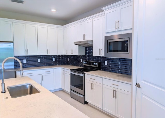 2729 Gabel Oak Dr, North Port, FL 34289 - kitchen with stainless steel appliances, under cabinet range hood, white cabinets, tasteful backsplash, and recessed lighting
