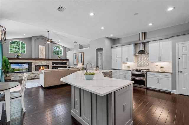 315 Lake Rd, Lake Mary, FL 32746 - kitchen featuring double oven range, a center island with sink, a ceiling fan, light stone counters, and dark wood finished floors