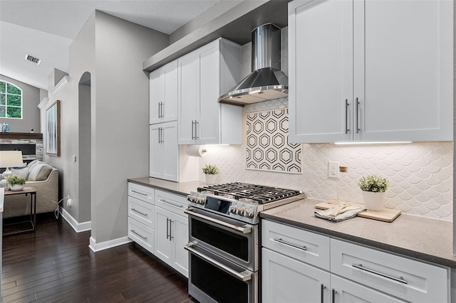 315 Lake Rd, Lake Mary, FL 32746 - kitchen featuring range with two ovens, wall chimney range hood, dark wood-type flooring, tasteful backsplash, and white cabinetry