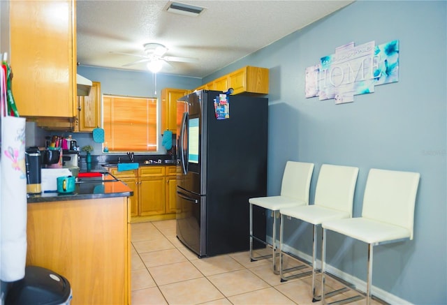 339 Colony Ct, Kissimmee, FL 34758 - kitchen featuring freestanding refrigerator, ceiling fan, dark countertops, light tile patterned flooring, and a textured ceiling