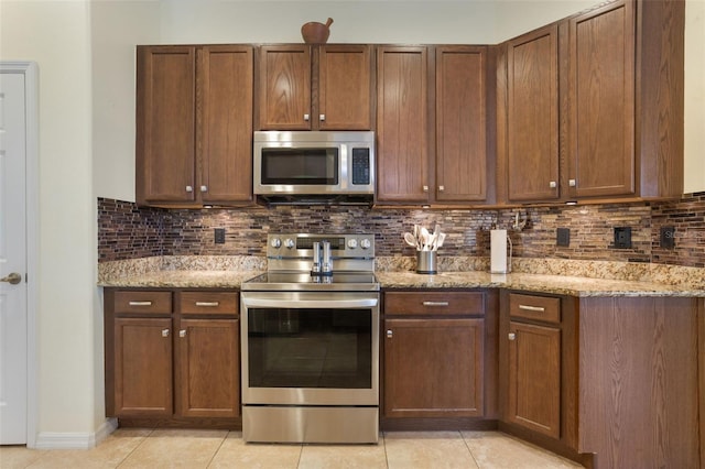 930 Willow Oak Loop, Minneola, FL 34715 - kitchen with appliances with stainless steel finishes, light tile patterned flooring, backsplash, and light stone counters