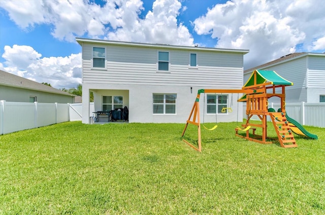 2149 Tudor Rose Dr, Sanford, FL 32773 - rear view of house with a playground, a fenced backyard, and stucco siding