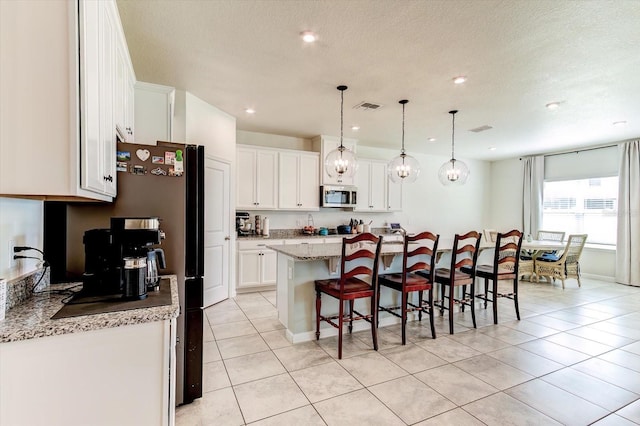 2149 Tudor Rose Dr, Sanford, FL 32773 - kitchen with stainless steel microwave, a kitchen breakfast bar, white cabinets, an island with sink, and light tile patterned floors