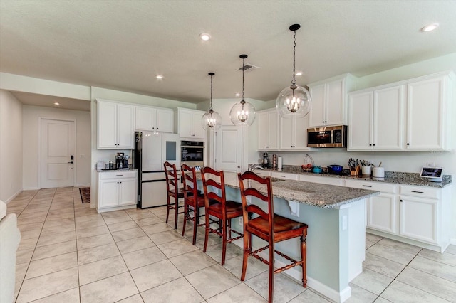 2149 Tudor Rose Dr, Sanford, FL 32773 - kitchen with stainless steel appliances, a kitchen island with sink, white cabinetry, light tile patterned floors, and a breakfast bar area