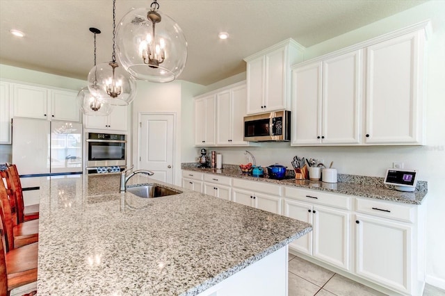 2149 Tudor Rose Dr, Sanford, FL 32773 - kitchen featuring appliances with stainless steel finishes, white cabinets, a center island with sink, a chandelier, and light stone countertops
