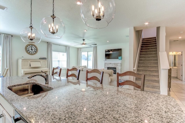 2149 Tudor Rose Dr, Sanford, FL 32773 - kitchen with a chandelier, a fireplace, ceiling fan, light tile patterned floors, and a textured ceiling