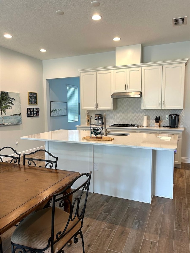 2042 Key Bay Trl, Kissimmee, FL 34747 - kitchen with dark wood-style floors, light countertops, under cabinet range hood, white cabinets, and recessed lighting