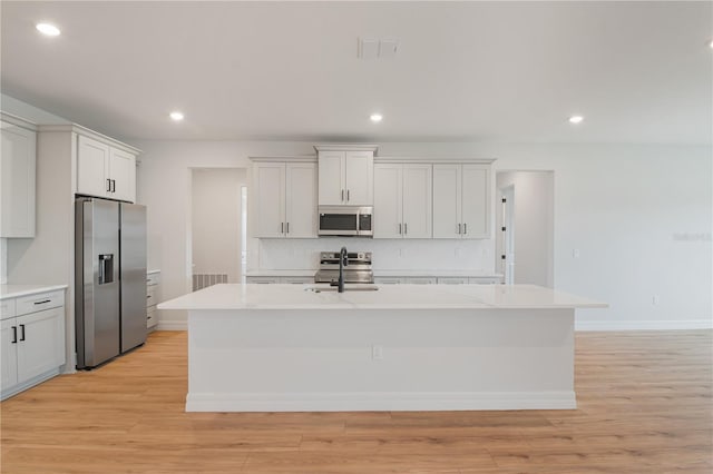 5908 SW 115 Street Rd, Ocala, FL 34476 - kitchen with appliances with stainless steel finishes, backsplash, a center island with sink, light wood-style flooring, and recessed lighting