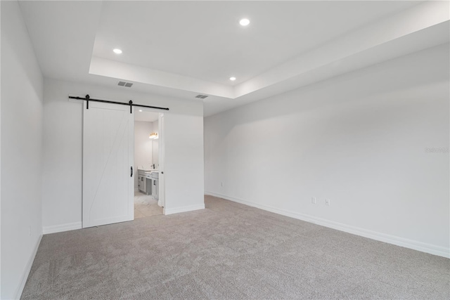 5908 SW 115 Street Rd, Ocala, FL 34476 - unfurnished bedroom featuring a barn door, light carpet, recessed lighting, a raised ceiling, and connected bathroom