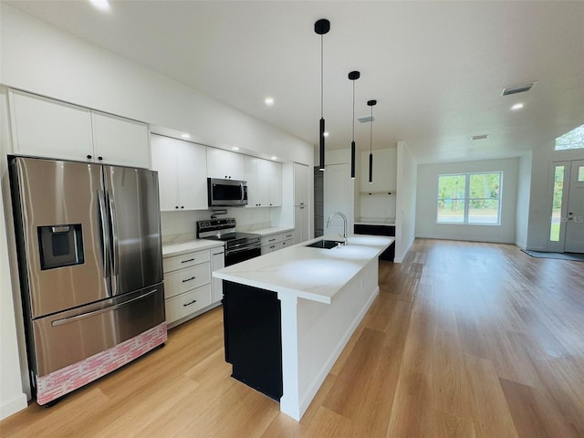 2664 SW De Groodt Rd, Palm Bay, FL 32908 - kitchen featuring stainless steel appliances, light wood-style floors, white cabinets, light countertops, and decorative light fixtures