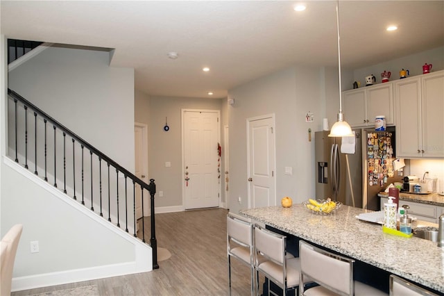 5963 Glory Bower Dr, Winter Garden, FL 34787 - kitchen with stainless steel fridge, recessed lighting, light wood-type flooring, a breakfast bar area, and light stone countertops