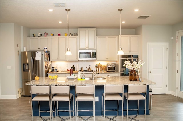 5963 Glory Bower Dr, Winter Garden, FL 34787 - kitchen featuring stainless steel appliances, light wood-style flooring, a kitchen island with sink, a breakfast bar, and recessed lighting