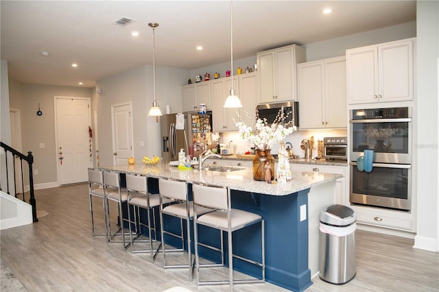 5963 Glory Bower Dr, Winter Garden, FL 34787 - kitchen featuring stainless steel appliances, a spacious island, light wood-style flooring, a kitchen breakfast bar, and recessed lighting