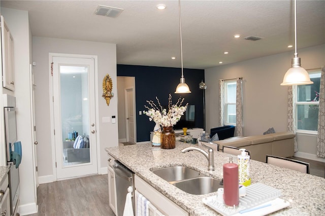 5963 Glory Bower Dr, Winter Garden, FL 34787 - kitchen with stainless steel dishwasher, light wood-style flooring, white cabinets, recessed lighting, and light stone counters
