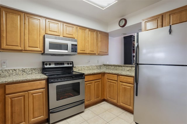 940 Douglas Ave Unit 159, Altamonte Springs, FL 32714 - kitchen featuring stainless steel appliances, light tile patterned floors, light stone counters, and brown cabinets