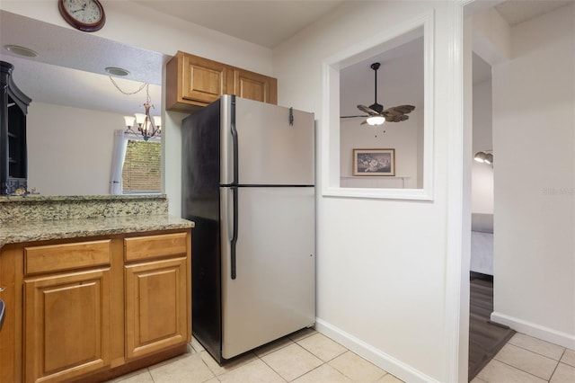 940 Douglas Ave Unit 159, Altamonte Springs, FL 32714 - kitchen featuring freestanding refrigerator, light tile patterned floors, a ceiling fan, brown cabinets, and light stone countertops