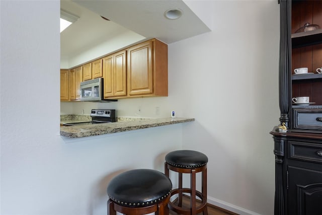 940 Douglas Ave Unit 159, Altamonte Springs, FL 32714 - kitchen with electric range oven, stainless steel microwave, a breakfast bar, open shelves, and wood finished floors
