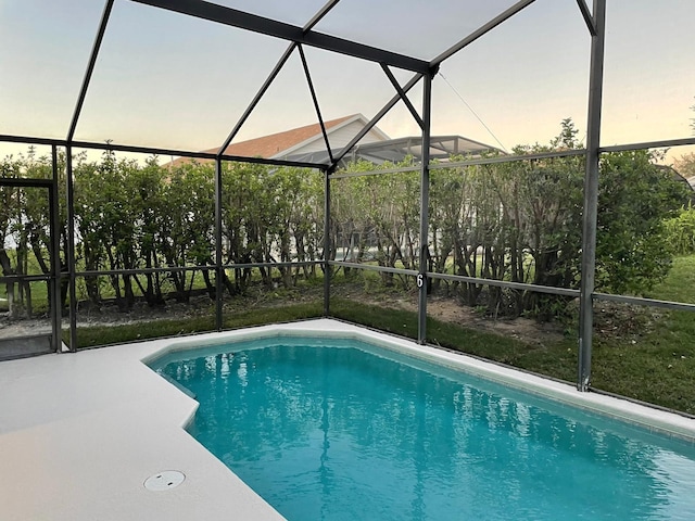2505 Osprey Creek Ct, Kissimmee, FL 34747 - pool at dusk featuring glass enclosure, an outdoor pool, and a patio area