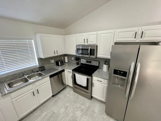 2505 Osprey Creek Ct, Kissimmee, FL 34747 - kitchen featuring appliances with stainless steel finishes, vaulted ceiling, white cabinets, light marble finish floors, and light countertops
