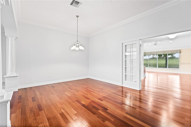 16950 SE 80th Bellavista Cir, The Villages, FL 32162 - spare room featuring decorative columns, hardwood / wood-style floors, crown molding, a textured ceiling, and a chandelier