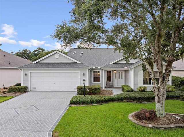 16950 SE 80th Bellavista Cir, The Villages, FL 32162 - view of front of home with decorative driveway, an attached garage, a front yard, and a shingled roof