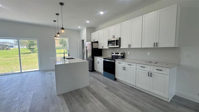 482 Marion Oaks Mnr, Ocala, FL 34473 - kitchen with stainless steel appliances, light wood-type flooring, white cabinets, recessed lighting, and a center island with sink