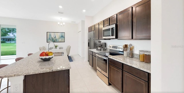 248 SW Cadence Gln, Lake City, FL 32024 - kitchen with appliances with stainless steel finishes, a kitchen island with sink, a chandelier, dark brown cabinetry, and light tile patterned flooring