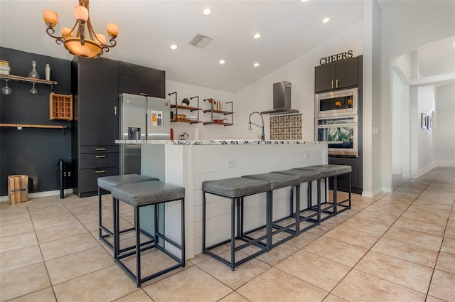 1315 Vista Del Lago Blvd, Dundee, FL 33838 - kitchen with appliances with stainless steel finishes, lofted ceiling, open shelves, wall chimney range hood, and a kitchen bar