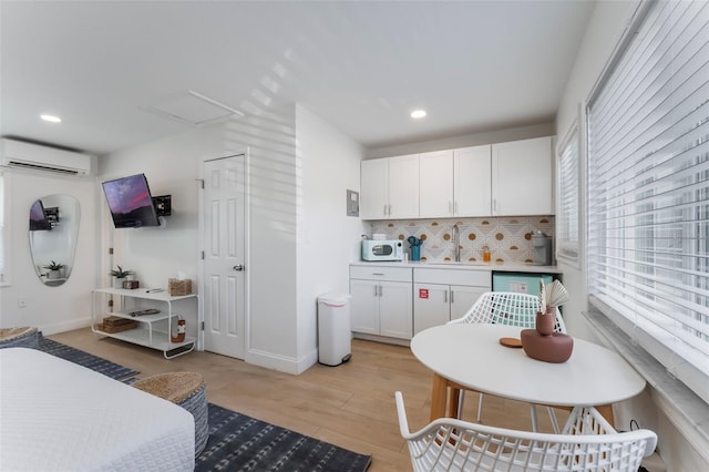 402 S Orlando Ave, Cocoa Beach, FL 32931 - kitchen with a wall mounted air conditioner, tasteful backsplash, white cabinetry, recessed lighting, and light wood-type flooring