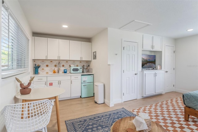 402 S Orlando Ave, Cocoa Beach, FL 32931 - kitchen with light wood-style flooring, decorative backsplash, light countertops, white cabinets, and recessed lighting
