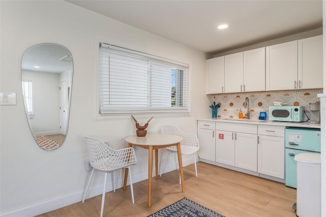 402 S Orlando Ave, Cocoa Beach, FL 32931 - kitchen with white microwave, light wood finished floors, white cabinetry, tasteful backsplash, and light countertops
