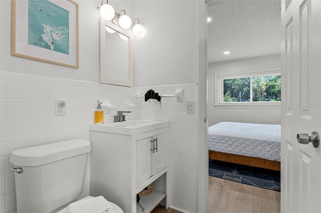 402 S Orlando Ave, Cocoa Beach, FL 32931 - bathroom featuring wood finished floors, vanity, tile walls, a textured ceiling, and wainscoting