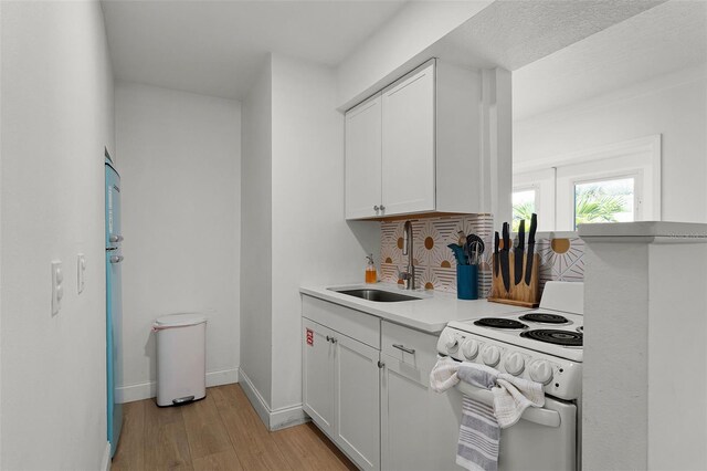 402 S Orlando Ave, Cocoa Beach, FL 32931 - kitchen featuring white electric stove, light wood finished floors, white cabinets, and backsplash