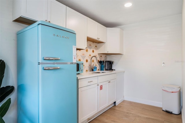 402 S Orlando Ave, Cocoa Beach, FL 32931 - kitchen with freestanding refrigerator, light wood-style flooring, tasteful backsplash, white cabinetry, and light countertops