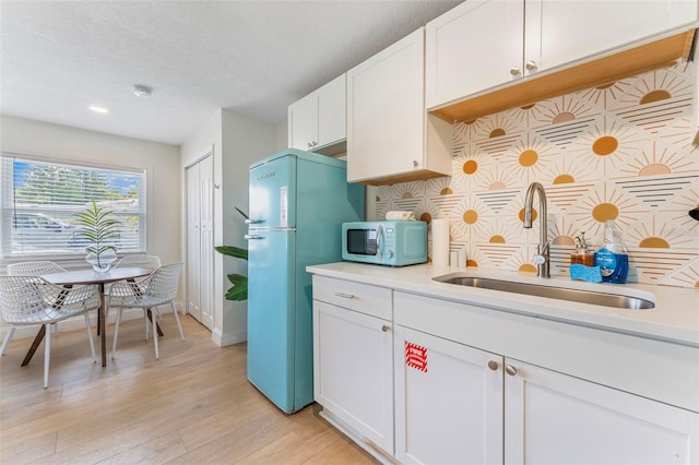 402 S Orlando Ave, Cocoa Beach, FL 32931 - kitchen featuring freestanding refrigerator, tasteful backsplash, light countertops, light wood-type flooring, and white cabinets