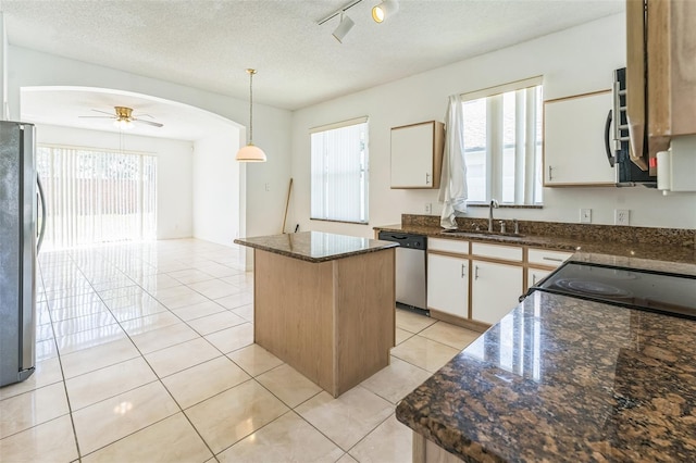 2110 Mallard Creek Cir, Kissimmee, FL 34743 - kitchen with appliances with stainless steel finishes, a kitchen island, healthy amount of natural light, arched walkways, and a textured ceiling