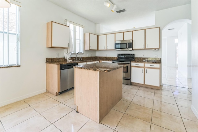 2110 Mallard Creek Cir, Kissimmee, FL 34743 - kitchen with appliances with stainless steel finishes, arched walkways, a kitchen island, dark stone countertops, and light tile patterned floors